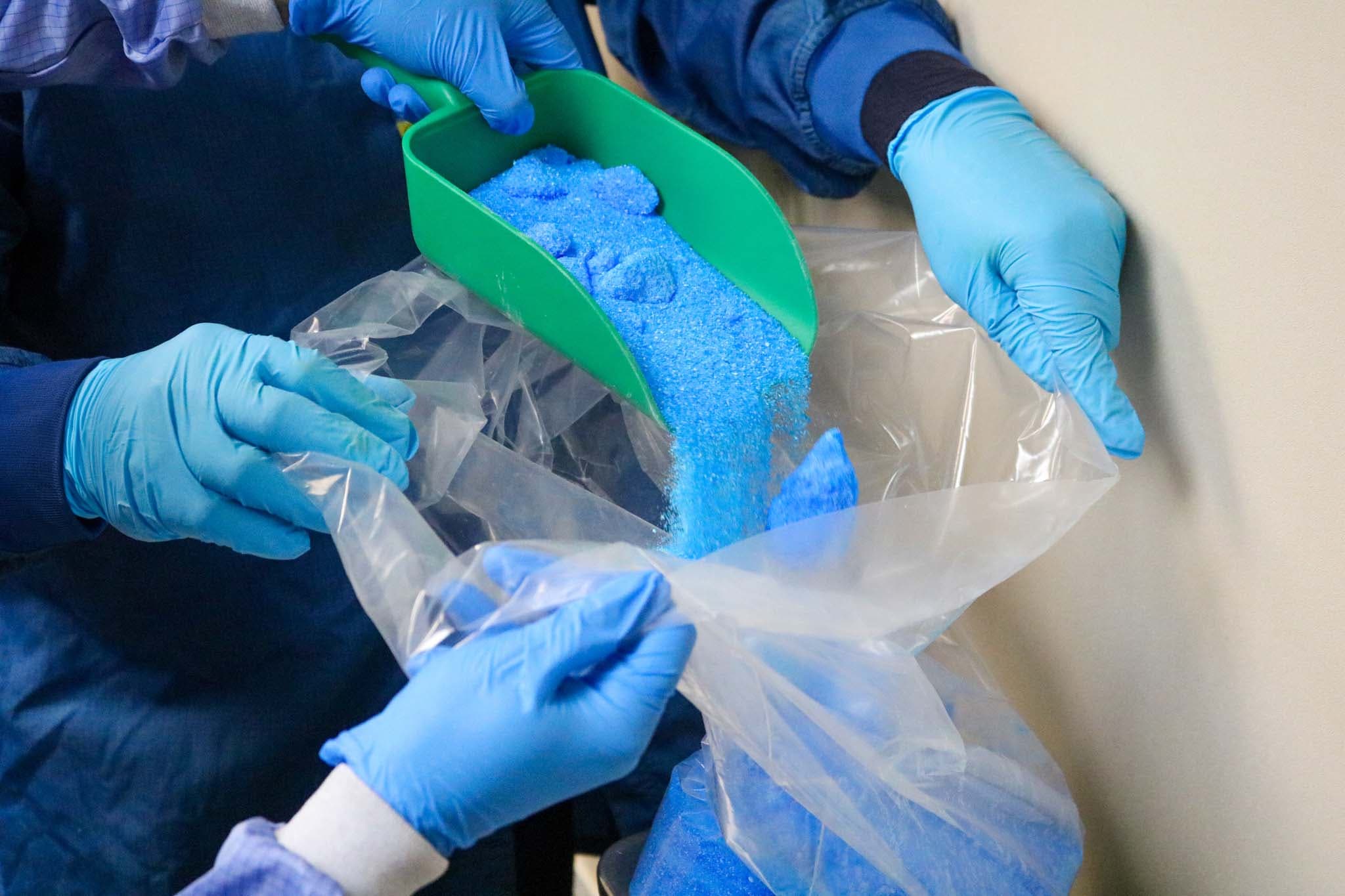 Raw ingredients being handled with gloves during supplement production