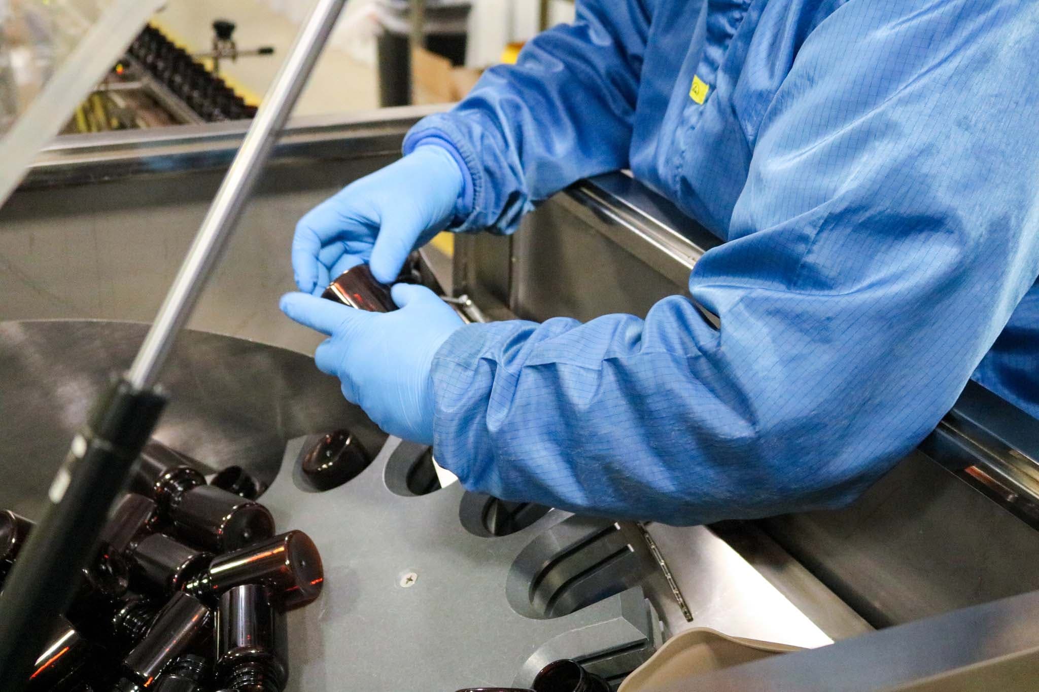 Production team member inspecting amber bottles on the filling line